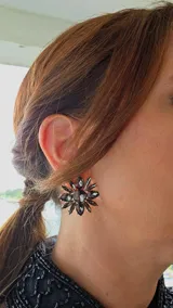 Caravana de diseño floral con pétalos de cristal oscuro en forma de gota y centro circular, montada sobre una base metálica dorada.