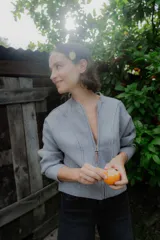 Campera de punto tipo bomber, color gris, con cierre frontal completo, cuello redondo y puños y ruedo acanalados. Presenta costuras decorativas verticales en el frente y tirador de cierre con detalle en cuero sintético.