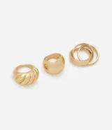 Kit de tres anillos para mujer con baño dorado. Incluye un anillo con diseño torcido tipo croissant, un anillo liso de banda ancha y un anillo triple compuesto por tres aros entrelazados de diferentes grosores. Fabricados en metal reciclado.