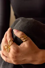 Anillo de diseño abierto y forma sinuosa, fabricado en acero quirúrgico con acabado pulido brillante.