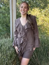 Camisa de lino azul marino con volados en cascada a lo largo del frente y en los puños de las mangas largas. Presenta un escote en V con un botón de nácar visible.