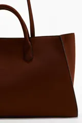 Cartera tote color marrón con doble asa de mano y correas finas para el hombro. Cuenta con cierre de mosquetón en el interior y un compartimento interior con cierre.