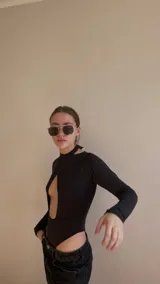 Body negro de lycra con escote cruzado y abertura en el pecho, atado atrás en el cuello y mangas largas.