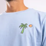 Remera celeste con cuello redondo y manga corta. Estampado pequeño de una palmera y un sol en el pecho.