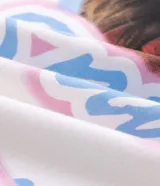 Remera de algodón con corte boxy, cuello redondo y mangas cortas. Presenta una estampa frontal con la imagen de Britney Spears rodeada por un corazón azul y gráficos decorativos en tonos rosados y celestes.