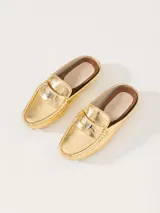 Mocasín tipo mule (destalonado) de cuero vacuno flor con textura croco, color dorado metalizado. Presenta un detalle metálico en forma de corazón sobre el empeine y suela de goma con relieve.