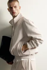 Chaqueta relaxed fit color beige melange, con cuello subido, manga larga y cierre frontal de cremallera. Cuenta con bolsillos de vivo en la cadera y acabados en rib.