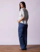 Blusa blanca estampada con flores azules, escote en V y mangas cortas amplias. Detalles de puntilla en escote y mangas.