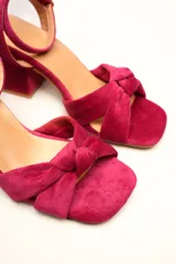 Sandalia de tacón cuadrado medio, confeccionada en terciopelo negro. Presenta un diseño de tiras cruzadas con nudo en la parte delantera y una tira ajustable con hebilla en el tobillo.