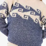 Buzo de tejido de punto con diseño bicolor en tonos crema y azul, con patrón geométrico estilo grecas en la parte superior. Presenta cuello redondo, mangas largas y terminaciones en tejido acanalado.