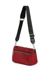 Bandolera pequeña de material sintético color beige claro, con cierre de cremallera frontal y correa ancha ajustable de tela negra.