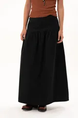Pollera larga de color negro con corte a la cadera y detalle de frunce que aporta volumen y movimiento a la prenda. Confeccionada en tela suave con acabado tipo piel de durazno.