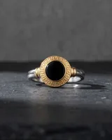 Anillo de plata 925 con diseño redondo, piedra ónix central y detalle de lámina de oro de 18k con guarda griega alrededor.