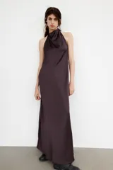 Vestido largo de satén negro con cuello halter y escote fluido. Presenta cierre con cremallera oculta en la espalda y lazada en el cuello.