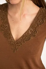 Remera color marrón con cuello redondo y detalle de encaje en el escote, de corte recto y manga corta.