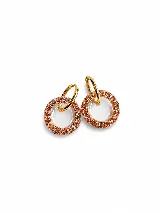 Aros colgantes compuestos por un aro superior dorado y un dije circular con centro translúcido y borde revestido de strass en tono dorado.