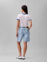 Remera cropped de manga corta color rosa pálido, con cuello redondo y ribetes azules. Estampado frontal con el logo de Calvin Klein y la inscripción 'New York City' en azul.