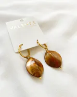 Aros colgantes con aro dorado y dije con forma de hoja con efecto marmolado en tonos marrones, naranjas y blancos.