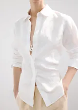 Camisa de lino blanca de corte recto, con cuello camisero, mangas largas y cierre frontal oculto de botones.