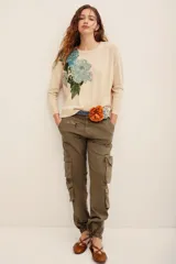 Sweater beige de punto con diseño de flores bordadas en tonos celestes y verdes en el frente, de cuello redondo y manga larga.