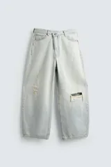 Jeans de mezclilla, tiro medio, color celeste claro lavado con efecto desgastado y roturas pronunciadas en ambas piernas. Corte ancho y relajado.
