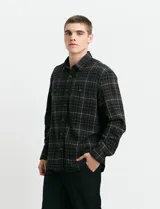 Camisa de franela a cuadros con cuello button-down, manga larga y botones de madera. Presenta dos bolsillos tipo parche en el frente con cierre de botón.