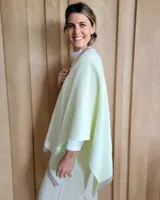 Ruana de tejido de punto en color crema con detalle de estrella grande en color verde lima en la espalda y bordes en tono arena.