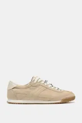Zapatillas deportivas color beige con pespuntes en el cuerpo, parte trasera en contraste de color y cierre mediante cordones. La altura de la suela es de 2 cm.