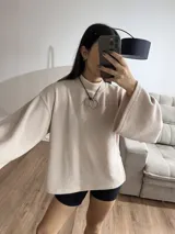 Polerón de cuello alto en color rosa suave, con diseño de calce holgado y mangas amplias. Presenta una textura acanalada fina y un corte relajado que aporta movimiento.