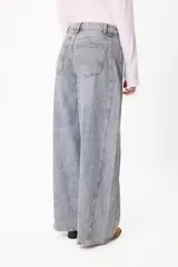 Jean de corte barrel con diseño de pierna ancha y tiro medio, confeccionado en denim de lavado claro. Presenta costuras laterales marcadas y un pequeño bordado del logo en el bolsillo delantero.