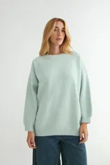 Buzo de tejido de punto color verde menta, con cuello redondo, mangas largas y corte holgado.
