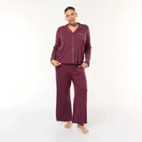Conjunto de pijama de dos piezas color bordó, compuesto por una camisa de manga larga con cuello solapa, cierre frontal de botones y vivo en contraste, y un pantalón de corte recto y holgado con cintura elástica.