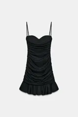 Vestido mini negro con escote corazón, aros en el busto y tirantes finos ajustables. Presenta un diseño drapeado en todo el cuerpo y un bajo con detalle de volante.