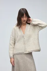 Cardigan de tejido de punto con textura, silueta boxy y cuello en V. Presenta cierre frontal con botones y detalles de terminación en contraste de color en los bordes.