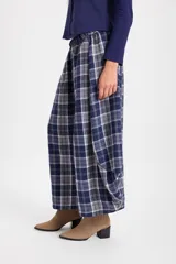 Pantalón de corte holgado con silueta tipo balloon, confeccionado en tela a cuadros. Presenta cintura elástica con cordón ajustable y cortes laterales circulares que aportan volumen a la prenda.