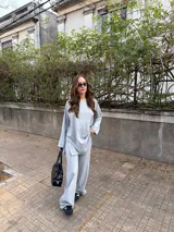 Conjunto de dos piezas de lanilla en color gris melange, compuesto por un buzo oversize de manga larga con aberturas laterales y un pantalón largo de corte recto y holgado.