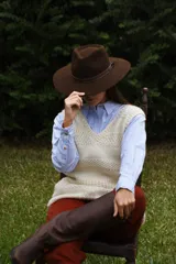 Sombrero marrón de ala ancha confeccionado en paño de lana afieltrada a mano, con cinta decorativa del mismo material alrededor de la copa.