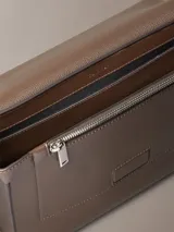 Cartera tipo mensajero con solapa y cierre magnético, confeccionada en piel sintética texturizada (micro pebble). Presenta correa ajustable y múltiples bolsillos interiores.