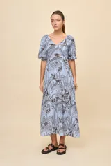 Vestido largo celeste con estampado botánico en tonos marrones, escote en V, mangas cortas abullonadas y falda con volado en el bajo.