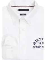 Camisa blanca de corte regular y manga larga, con logo bordado en el pecho y botón a contraste.