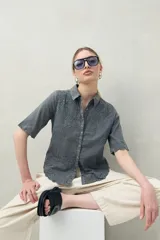 Camisa blanca de manga corta confeccionada en algodón, con bordados a tono y terminaciones festoneadas. Presenta cuello clásico y silueta recta.