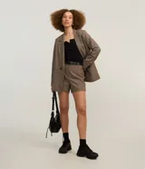 Short de sastrería color marrón con estampa de cuadros, cintura con trabillas y cierre delantero con cremallera.