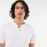 Remera blanca de manga corta con cuello tunecino y tres botones frontales.