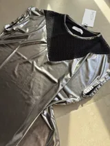 Remera plateada de efecto metalizado con un panel triangular de red negra en el pecho, cuello redondo y mangas cortas holgadas.