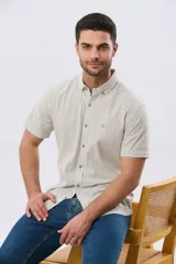 Camisa de manga corta confeccionada en mezcla de lino y algodón, con diseño de rayas verticales en tonos celeste y blanco. Cuenta con cuello camisero, botonadura frontal y bordado sutil en el pecho.