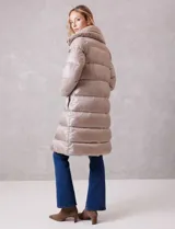 Campera puffer larga de acabado satinado en tono beige. Presenta un diseño capitoneado horizontal, cierre frontal bidireccional y un amplio cuello envolvente revestido en piel sintética. Incluye bolsillos laterales funcionales con cierre y logo metálico en la manga.