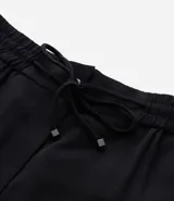 Pantalón de corte fluido y estilo pijama, color negro, con cintura elástica ajustable mediante lazo y detalle de tiras con hebilla en los tobillos.