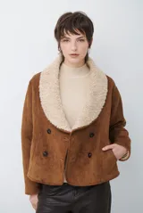 Chaqueta tipo gamulán de color marrón, con solapas amplias forradas en corderito sintético oscuro. Presenta un diseño cruzado con botones frontales y mangas largas, ideal para un estilo invernal.
