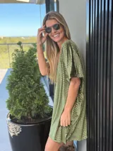 Vestido corto de terciopelo color marrón con textura de relieve tipo reptil, escote en V y corte holgado con mangas cortas.