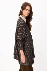 Sweater de tejido artesanal con diseño de rayas verticales en tonos camel y beige, corte holgado, cuello redondo y puños altos ajustados.